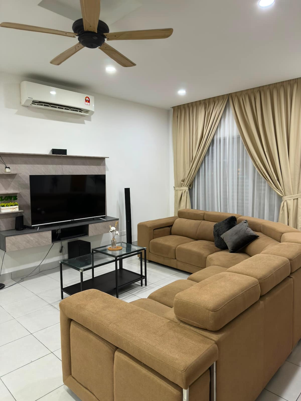 Living room with a sectional sofa, wall-mounted TV and ceiling fan