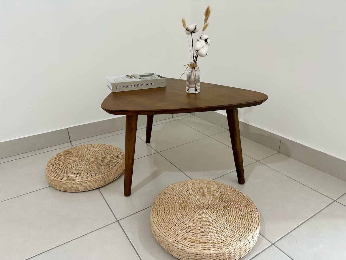 Lounge corner with a low wooden table, woven floor cushions and dried stems in a vase